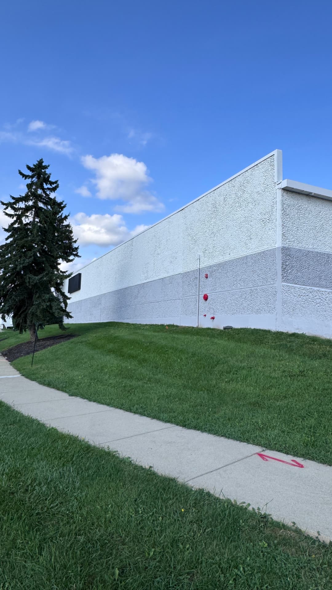 Corner elevation showing repainted wall field, banding, and downspout