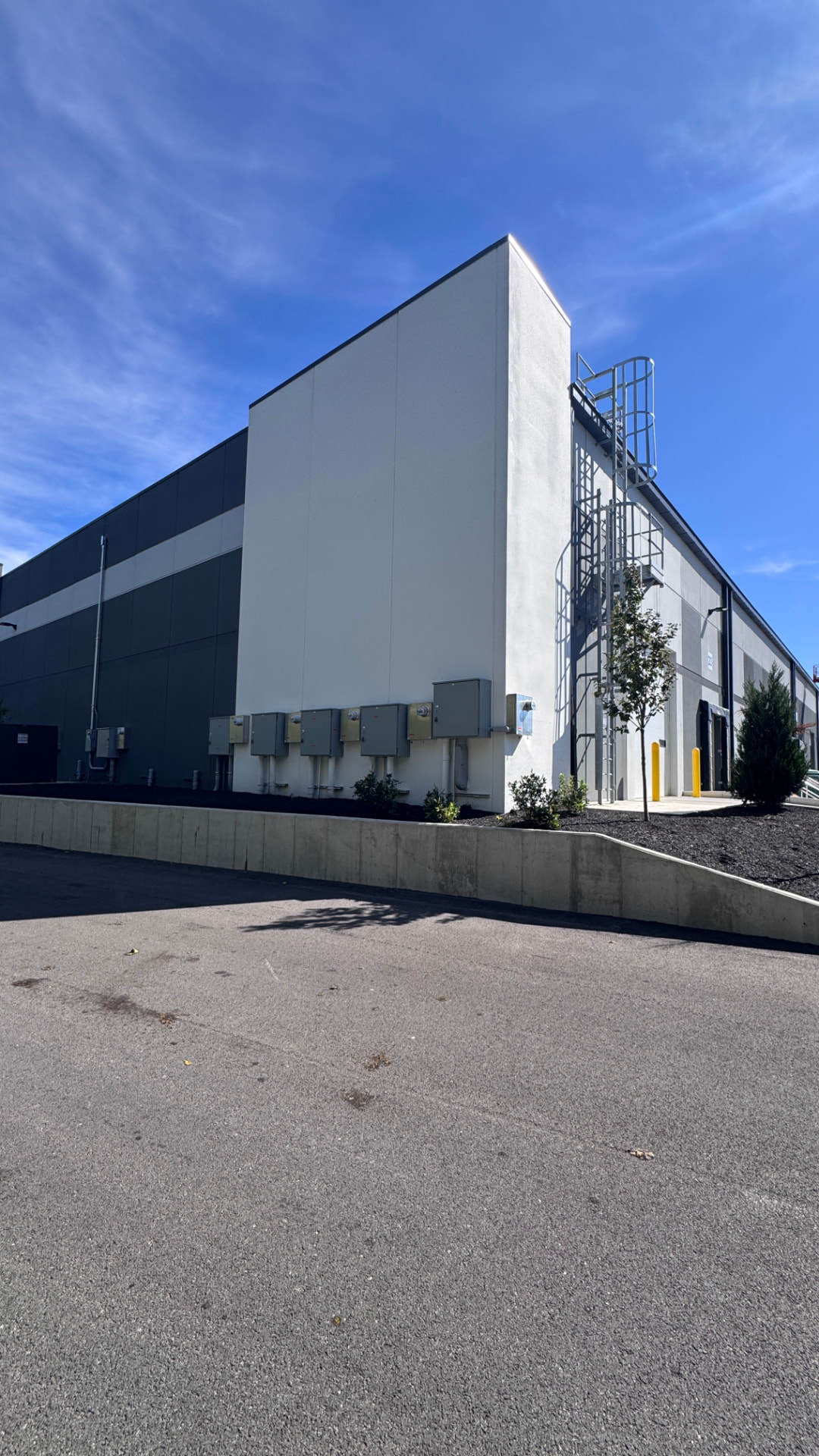 Corner elevation after full exterior repaint — white tower, gray banding, and wall field